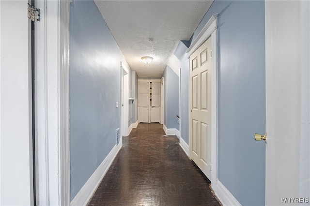 hall featuring a textured ceiling and dark wood-type flooring