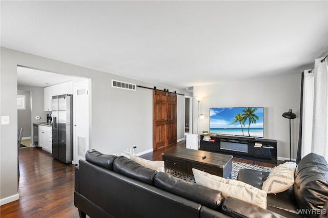 living room with a barn door and dark hardwood / wood-style floors