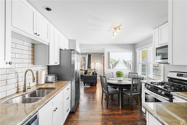 kitchen with sink, dark hardwood / wood-style flooring, light stone counters, white cabinetry, and stainless steel appliances