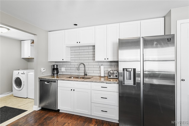 kitchen with washer and clothes dryer, white cabinets, dark hardwood / wood-style floors, and appliances with stainless steel finishes