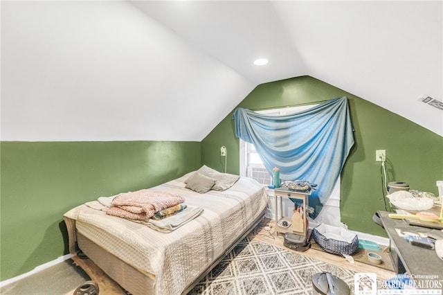 bedroom featuring visible vents, baseboards, wood finished floors, and vaulted ceiling