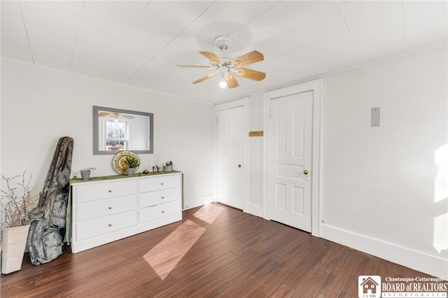 unfurnished bedroom with baseboards, dark wood finished floors, a ceiling fan, and crown molding