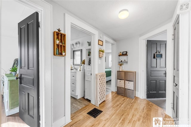 hall featuring a sink, light wood-type flooring, and visible vents