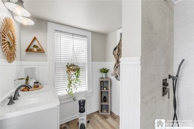 interior space with a wainscoted wall, vanity, and wood finished floors