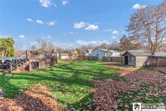 view of yard with an outbuilding, stairway, a fenced backyard, and a deck