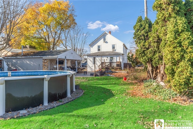 back of property featuring an outdoor pool, a yard, and a wooden deck