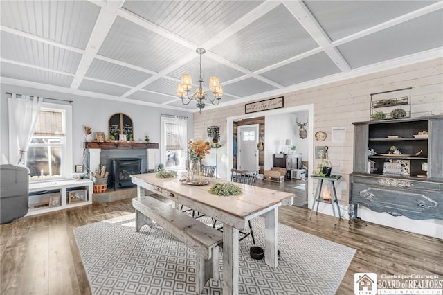 dining area featuring wooden walls, coffered ceiling, an inviting chandelier, and wood finished floors