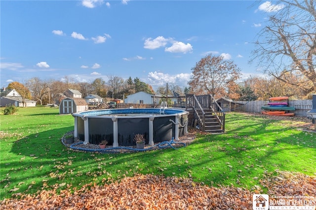 view of pool featuring a storage unit, an outbuilding, a lawn, a wooden deck, and a fenced in pool