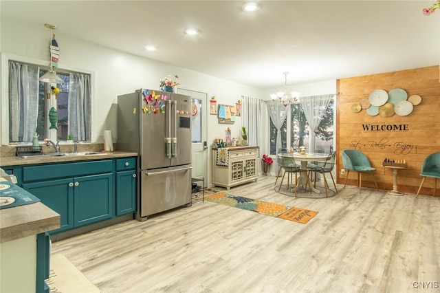 kitchen with sink, light hardwood / wood-style flooring, decorative light fixtures, wooden walls, and high end fridge