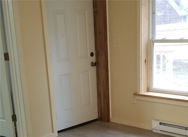 doorway to outside with light wood-type flooring and a baseboard heating unit