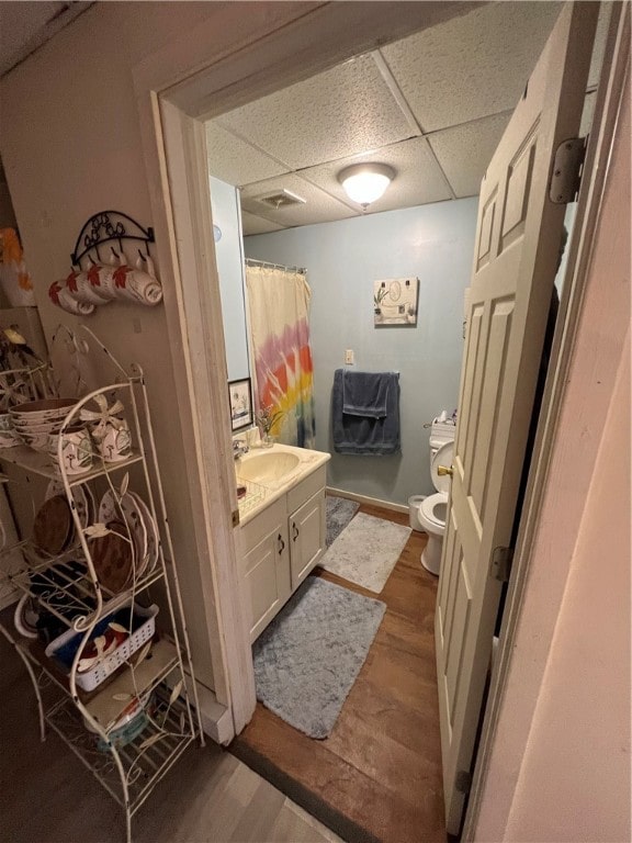 bathroom featuring hardwood / wood-style floors, a drop ceiling, toilet, and vanity