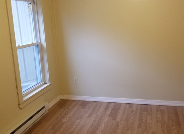 spare room featuring baseboard heating and light hardwood / wood-style flooring