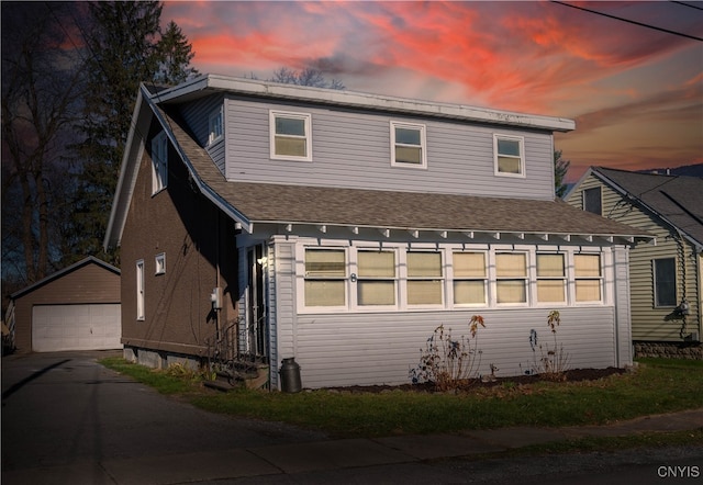 back house at dusk featuring a garage and an outbuilding