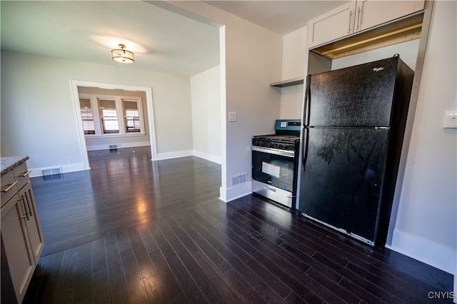 kitchen with dark hardwood / wood-style flooring, black refrigerator, and stainless steel gas range