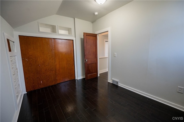 unfurnished bedroom featuring dark hardwood / wood-style floors, lofted ceiling, and a closet