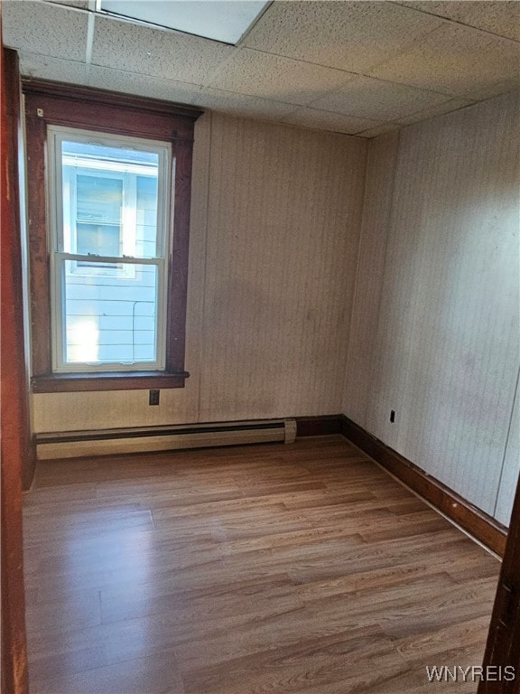 unfurnished room with a paneled ceiling, hardwood / wood-style floors, and a baseboard radiator