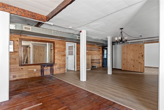 basement with wooden walls, dark hardwood / wood-style flooring, and an inviting chandelier