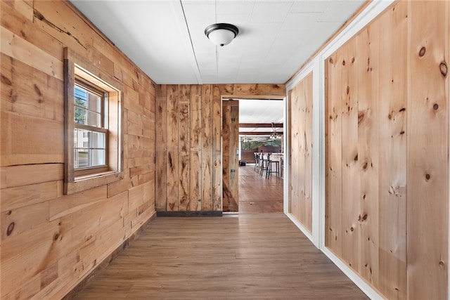 hall with wood-type flooring and wooden walls