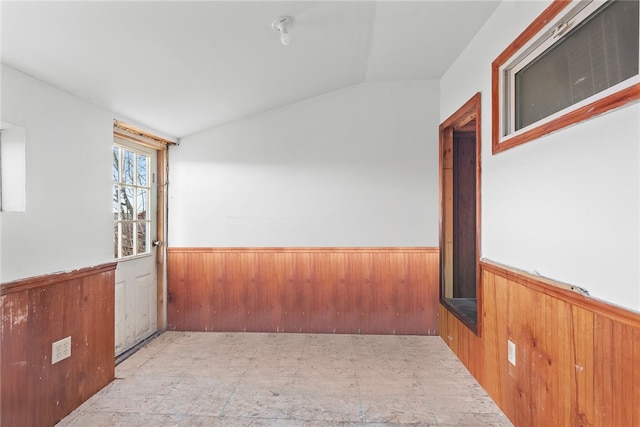 spare room featuring wooden walls and lofted ceiling