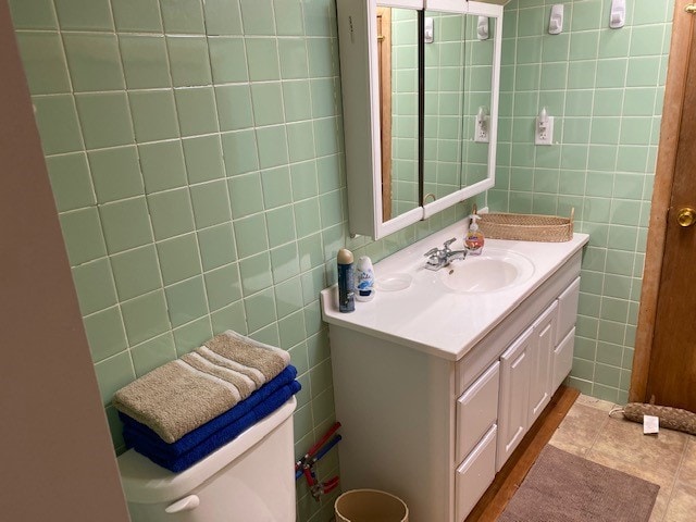 bathroom featuring vanity, toilet, and tile walls