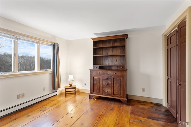 interior space with dark wood-type flooring and a baseboard heating unit