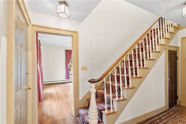 staircase with baseboard heating and wood-type flooring