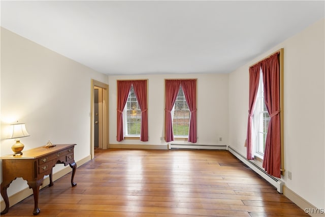 empty room with light hardwood / wood-style flooring and baseboard heating