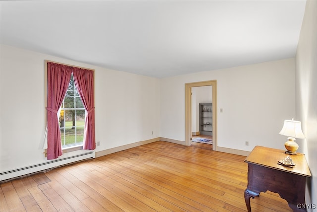 empty room featuring hardwood / wood-style floors and a baseboard heating unit