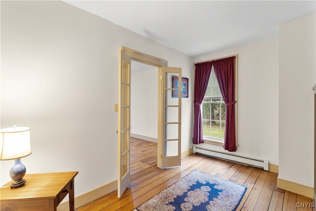 interior space featuring light wood-type flooring, baseboard heating, and french doors