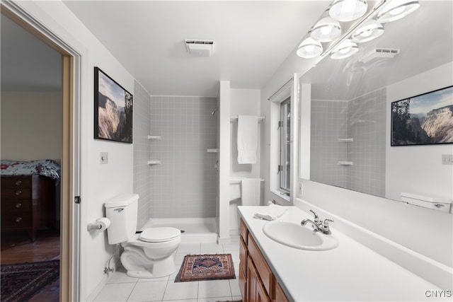 bathroom featuring tile patterned flooring, vanity, toilet, and tiled shower