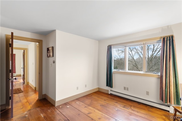 unfurnished room with wood-type flooring and baseboard heating