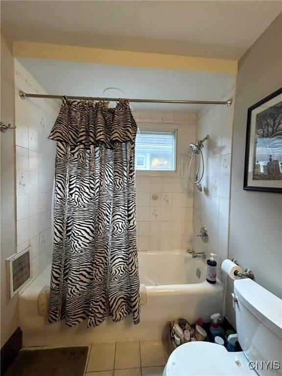 bathroom featuring tile patterned flooring, shower / bath combination with curtain, and toilet