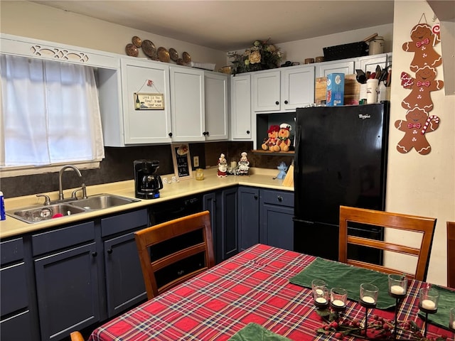 kitchen with backsplash, white cabinetry, black fridge, and sink