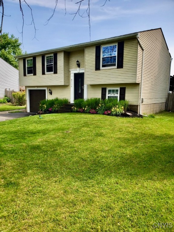 raised ranch featuring a front yard and a garage