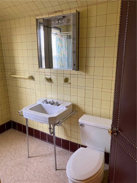 bathroom with toilet and tile walls