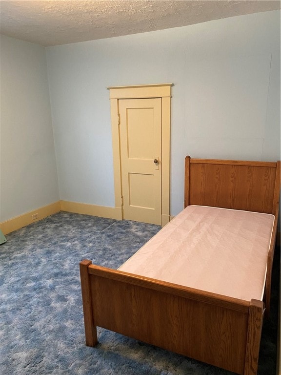 bedroom featuring dark colored carpet and a textured ceiling