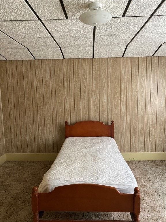 bedroom with a paneled ceiling and wooden walls