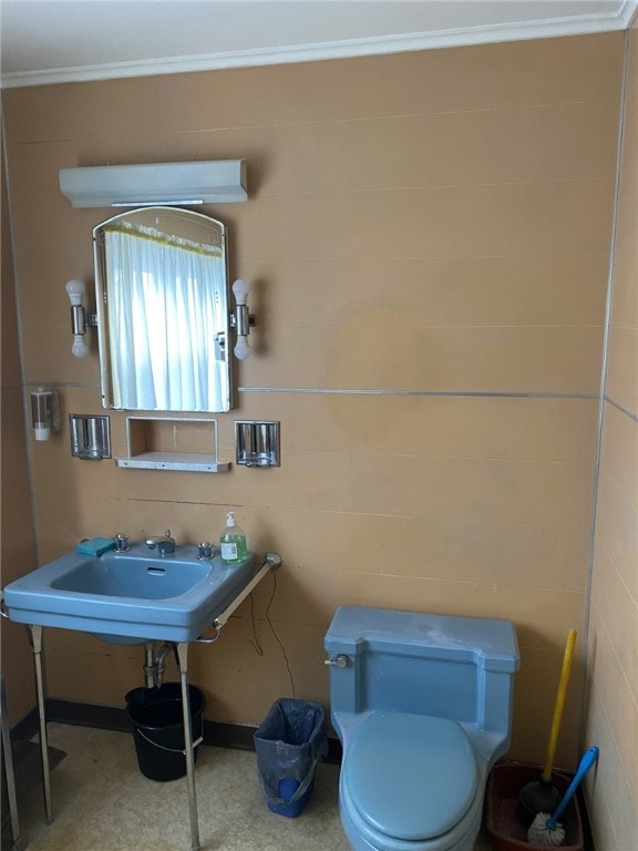 bathroom featuring toilet, ornamental molding, and tile walls