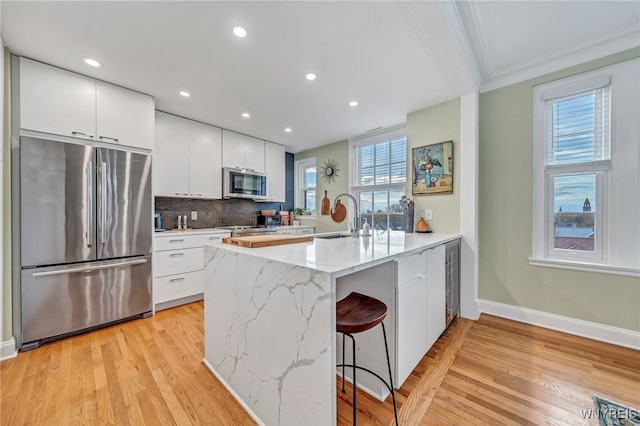 kitchen with a kitchen bar, kitchen peninsula, light hardwood / wood-style flooring, and appliances with stainless steel finishes