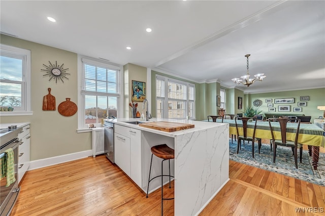 kitchen with sink, hanging light fixtures, an inviting chandelier, white cabinets, and light wood-type flooring