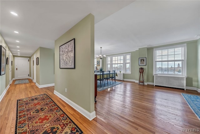 hall featuring a chandelier, wood-type flooring, and radiator heating unit