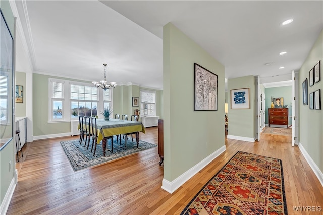 dining room with light hardwood / wood-style flooring, an inviting chandelier, and ornamental molding