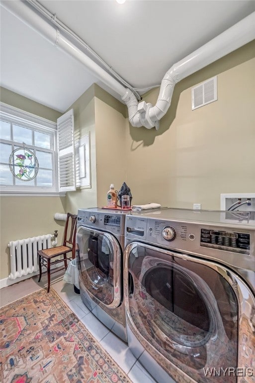 laundry area with radiator, light tile patterned floors, and washer and dryer