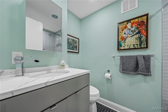 bathroom featuring tile patterned floors, vanity, toilet, and a shower