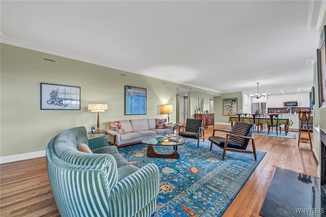 living room featuring wood-type flooring, ornamental molding, and a notable chandelier