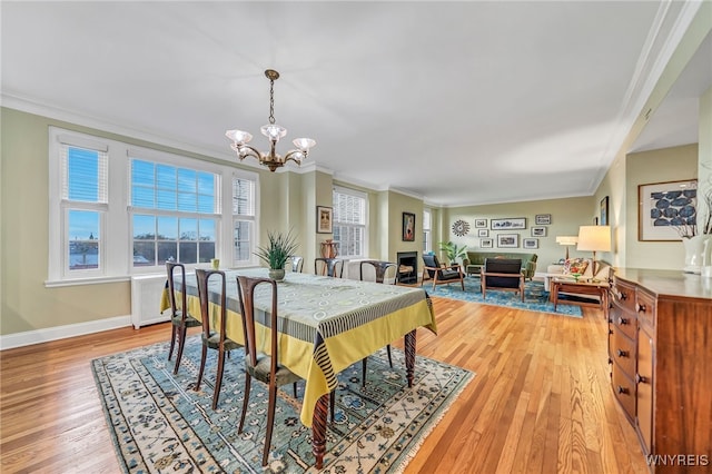 dining space featuring light hardwood / wood-style floors, crown molding, and a chandelier