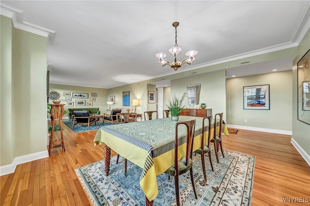 dining space featuring a chandelier, light hardwood / wood-style floors, and crown molding