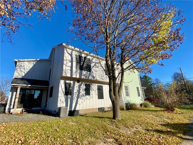 view of side of home with a lawn and central AC unit