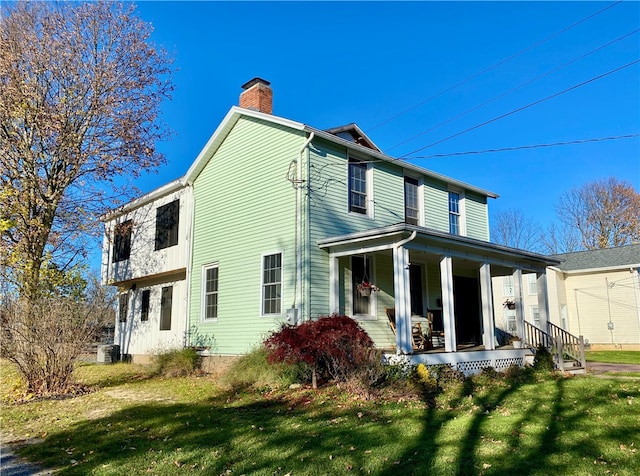 rear view of property featuring a porch and a lawn