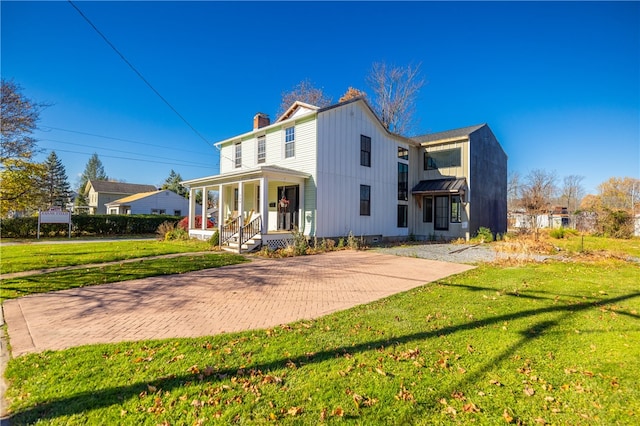 rear view of house featuring a lawn and a porch